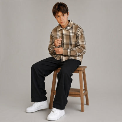 Ragazzo indossa una camicia a quadri in flanella Chulo Store color beige con bottoni, abbinata a pantaloni neri.