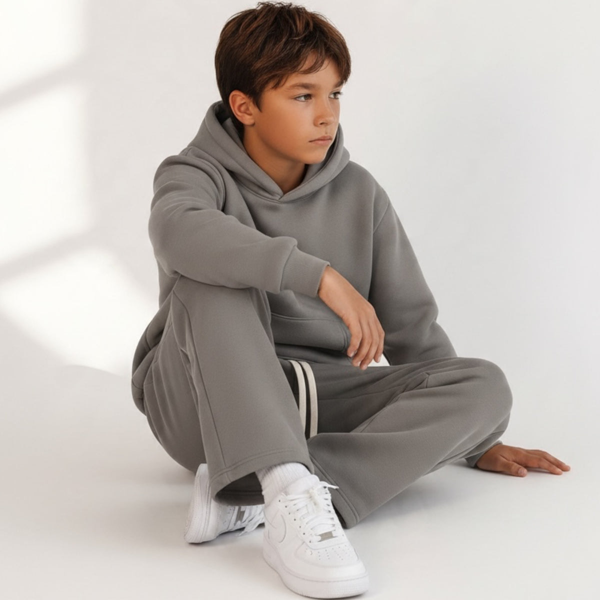 Ragazzo indossa completo Chulo Store grigio tortora con felpa con cappuccio e pantaloni sportivi in tessuto morbido