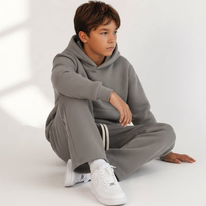 Ragazzo indossa completo Chulo Store grigio tortora con felpa con cappuccio e pantaloni sportivi in tessuto morbido