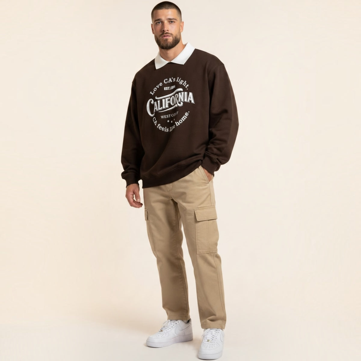 Modello indossa felpa Chulo Store marrone con colletto bianco a contrasto e grafica California su pantaloni cargo beige