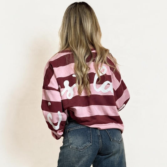 Modella di spalle indossa una felpa Chulo Store oversize a righe rosa e bordeaux con scritta bianca sul retro