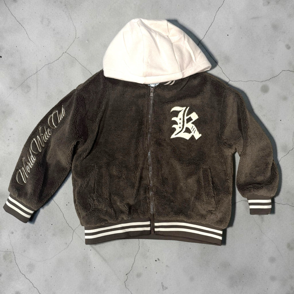 Giacca bomber Chulo Store in pile marrone con cappuccio crema, chiusura zip, polsini a righe e scritta World Wide Club