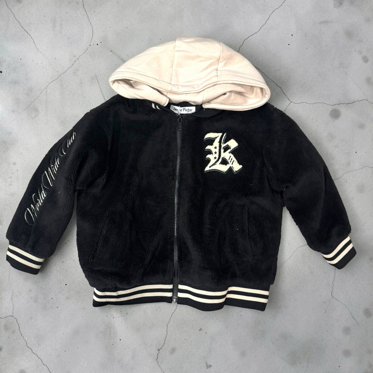 Giacca bomber Chulo Store in pile nero con cappuccio crema, chiusura zip, polsini a righe e scritta World Wide Club