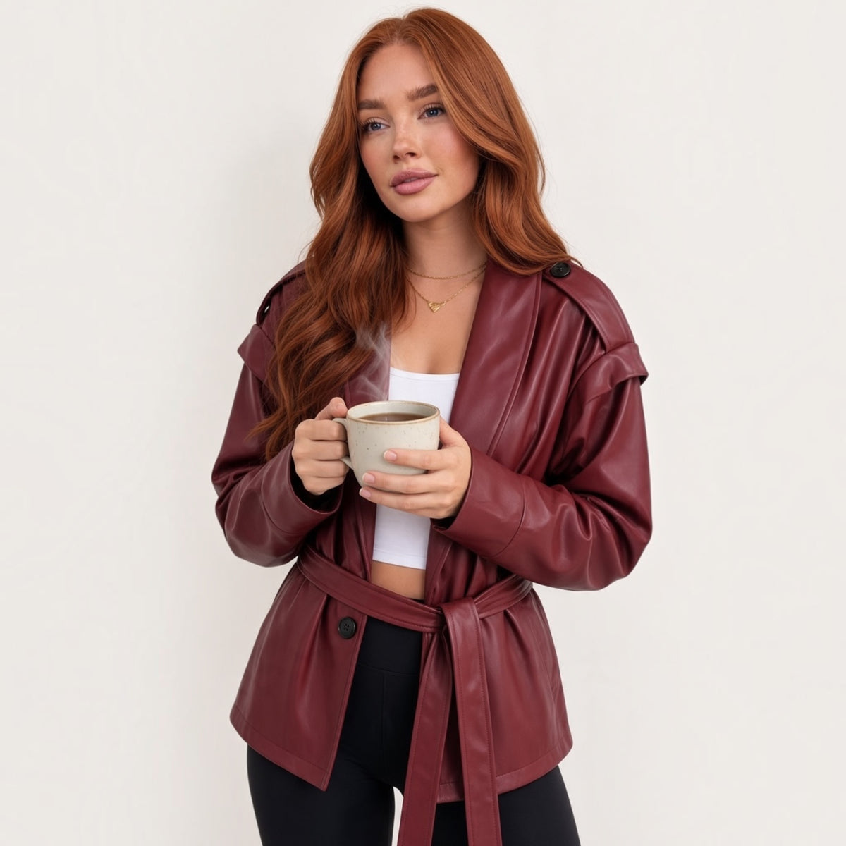 Modella con giacca Chulo Store in ecopelle bordeaux con cintura in vita e spalline strutturate, stile casual chic.