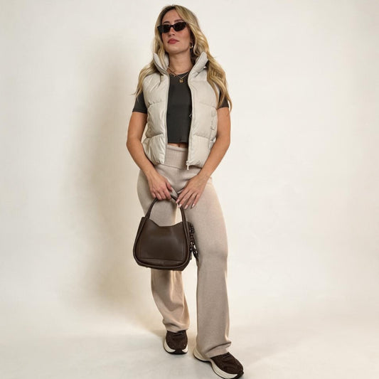 Modella indossa gilet imbottito Chulo Store color beige con collo alto, abbinato a pantaloni coordinati e borsa scura