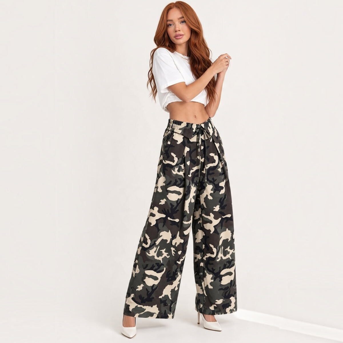 Modella indossa pantaloni Chulo Store a gamba larga con stampa camouflage, vita alta e coulisse, stile urban-chic.