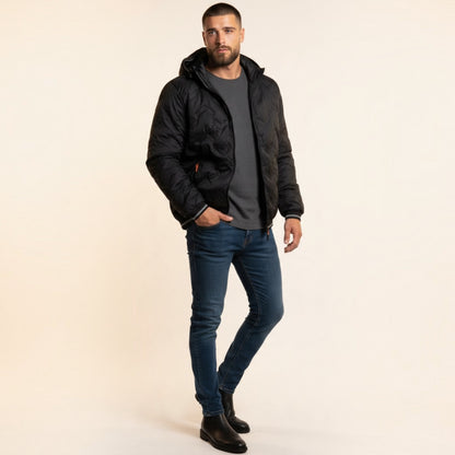 Modello indossa piumino nero Chulo Store con trapuntatura a onde, cappuccio e dettagli arancioni su sfondo neutro
