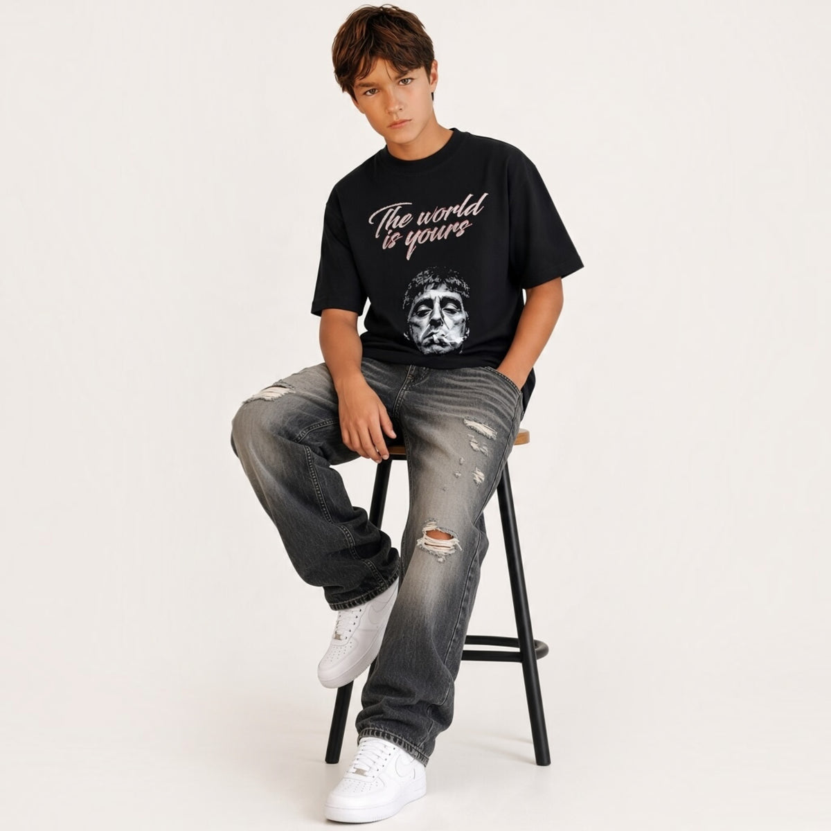 Ragazzo indossa una t-shirt nera Chulo Store in cotone con stampa grafica di Tony Montana e scritta The world is yours